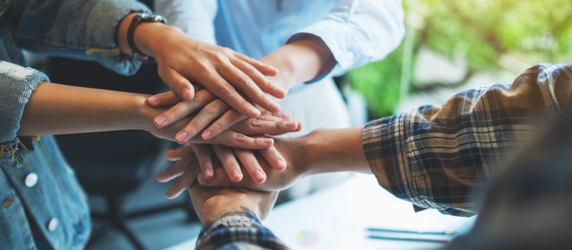 Closeup image of business team standing and joining their hands together in office
