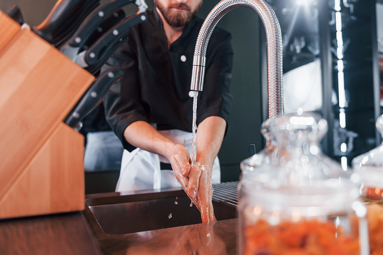 Restaurant owner in Marin County washes hands in a sink recently repaired by a commercial plumbing expert